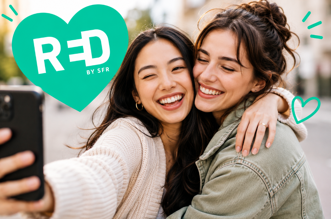Deux amies, prennent un selfie en se faisant un câlin devant un cœur représentant le logo RED by SFR, illustrant le parrainage SFR.